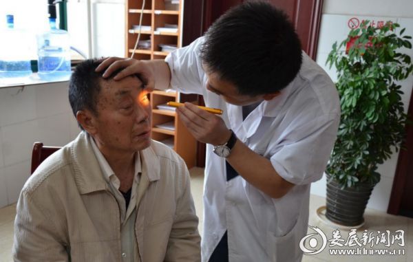苏主任为陈大爷检查眼部情况