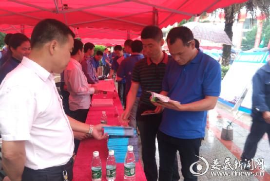 图为群众认真查看工伤保险宣传资料）