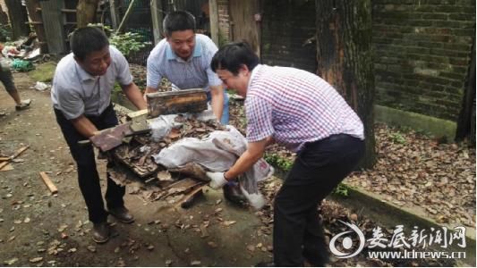 市供销社党组书记、理事会主任龚卫民（左）与市供销社党组副书记、监事会主任谭平贵（右），党员毛紫阳（中）搬运垃圾。