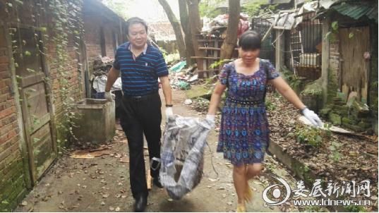 市供销社党组成员、理事会副主任张建军（左）与党员金淑兰（右）搬运垃圾