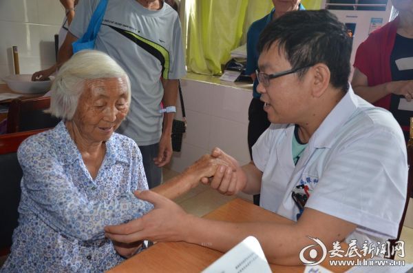 82岁的杜咸谷奶奶感激地握着娄底爱尔眼科医院白内障中心廖冠雄主任的手