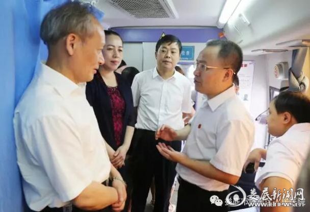 贺军民（右二）向郭光文（左）一行介绍“健康快车”大巴上的检查项目和设备