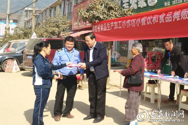 图为镇党委书记肖建军给过往群众宣讲食品安全知识
