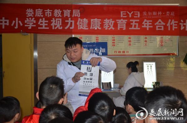 娄底爱尔眼科医院的工作人员耐心教孩子们看视力检测表