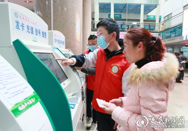 志愿者在门诊大厅指导患者使用自助机挂号.