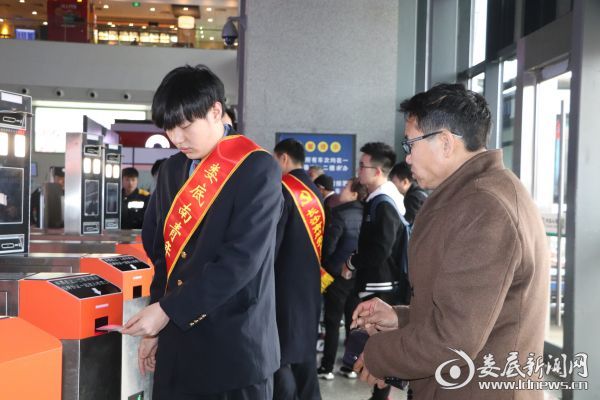 （志愿服务人员给不熟悉人脸识别验票的旅客示范操作）