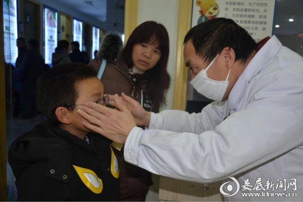 娄底爱尔眼科眼镜加工房的医务人员正在为孩子试戴加工好的眼镜