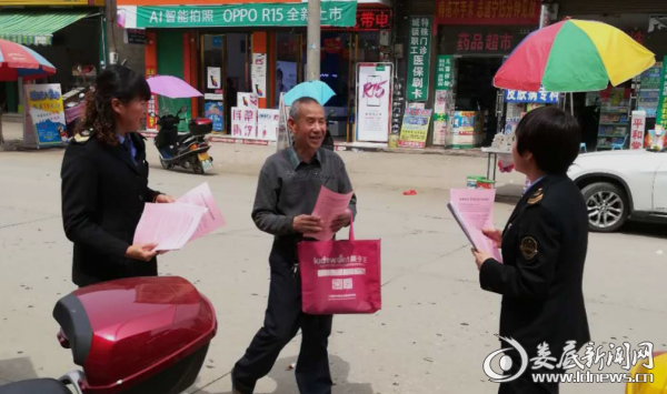 (工作人员向过往老年朋友发放“护老行动”宣传资料)