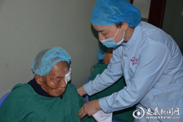 （搀扶九旬白内障老人走进手术室）