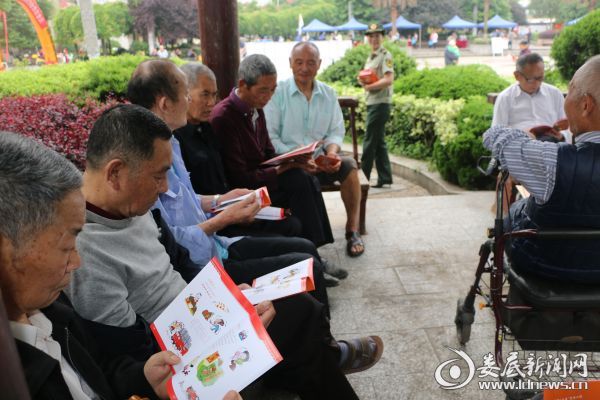 （老人们认真阅读消防安全知识手册）