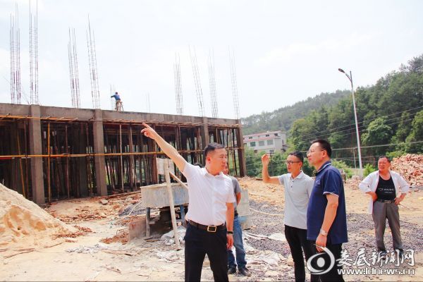图为邓志洪（右二）实地察看项目建设情况