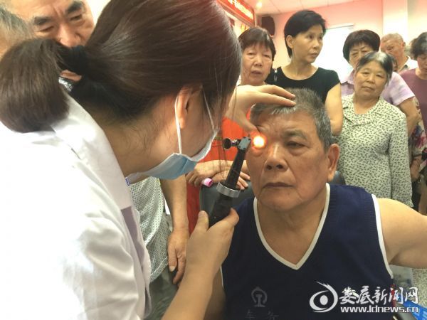84岁的张可亮老人在义诊现场接受眼部检查