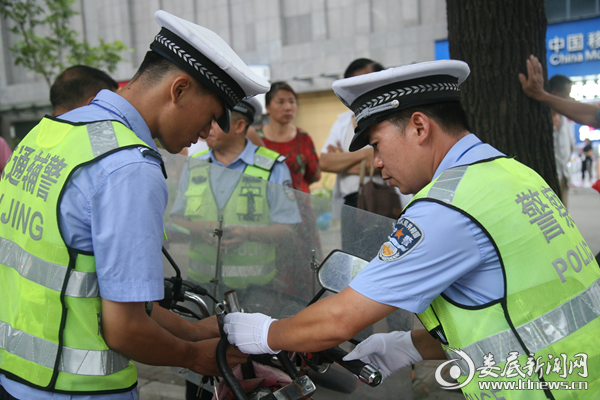 （执勤交警查获一台非法打伞的摩托车辆，在将伞拆除后还将伞把拆除，彻底消除安全隐患）