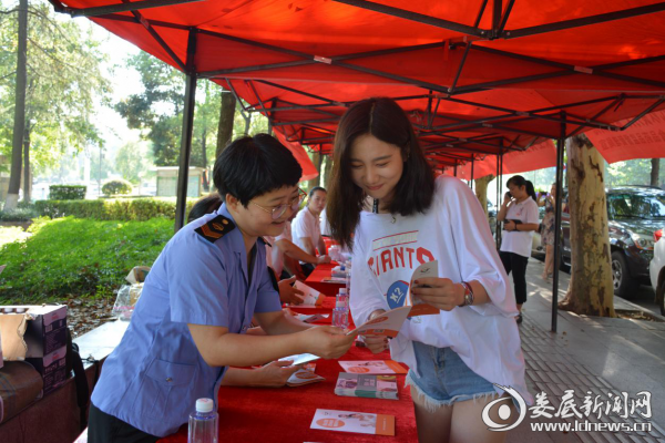 图为市食药监局工作人员向过往市民科普食品安全知识。