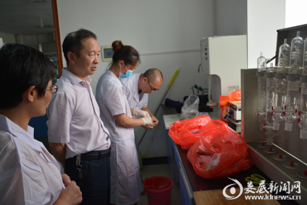图为市局党组书记、局长侯迪凡现场查看水产品检验。