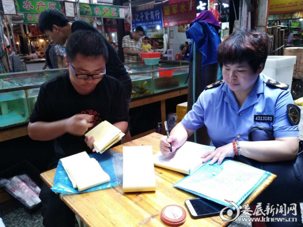 图为执法人员在认真填写抽检执法文书。