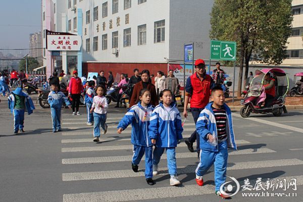 （放学时期，市卫计委党员志愿者在娄底八中护送孩子们过马路）