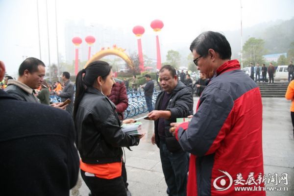 （活动现场，志愿者向过往群众发放宣传资料。）