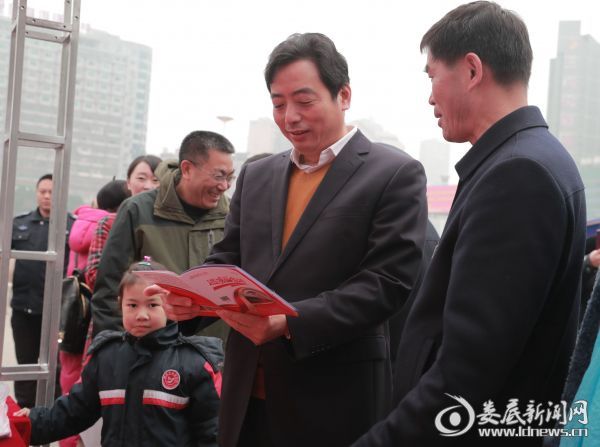 (吴建平仔细查看“温暖回家路”便民服务手册)