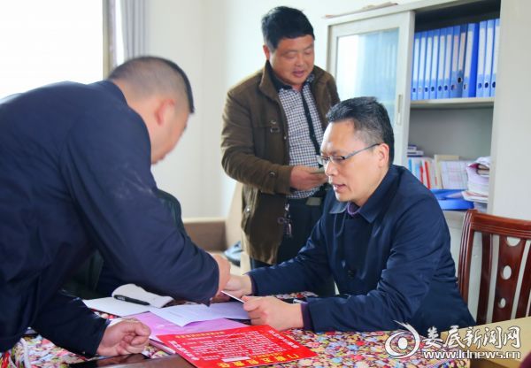 1图为市民政局党组书记、局长陈伟志（右一）查看芙蓉村扫黑除恶工作台账资料