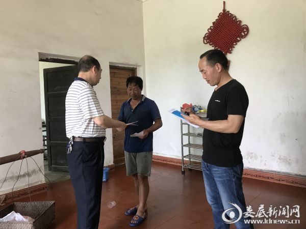 (工作人员向村民发放宣传资料)