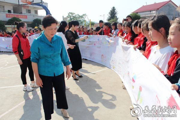 （伍美华为“迪丽热巴美术教室”授牌，并在画卷前一一观赏孩子们的绘画作品，了解他们的“微心愿”）