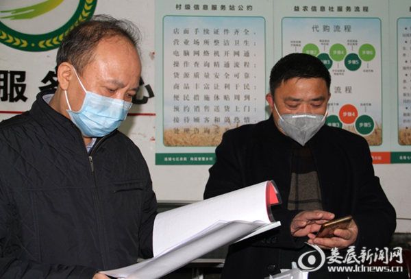 毛健刚（左）查看桥头河镇桂花村便民服务中心疫情摸排情况登记表