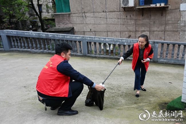 （志愿者们身穿红马甲、佩戴红袖章，手持各式清洁工具，兵分5组，深入社区各单元楼、巷路，对花坛、台阶、边石、路面等进行清扫、整理，对居住小区的牛皮鲜广告等进行涂抹、清除）