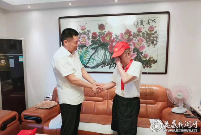 （中心党委书记、主任邱胜平上门为老党员颁送纪念章，老人激动抹泪）