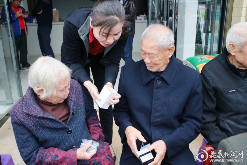 （拿到智能手机，老人们立即询问志愿者使用方法）