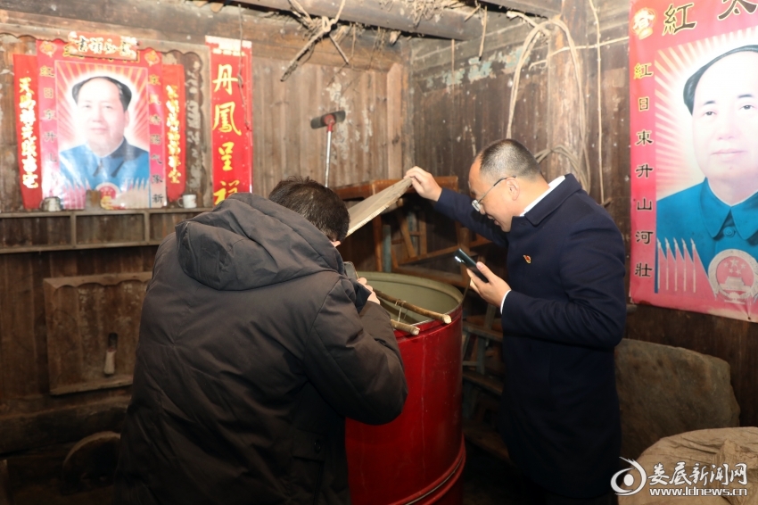 （吴润民察看脱贫户家中的米缸）