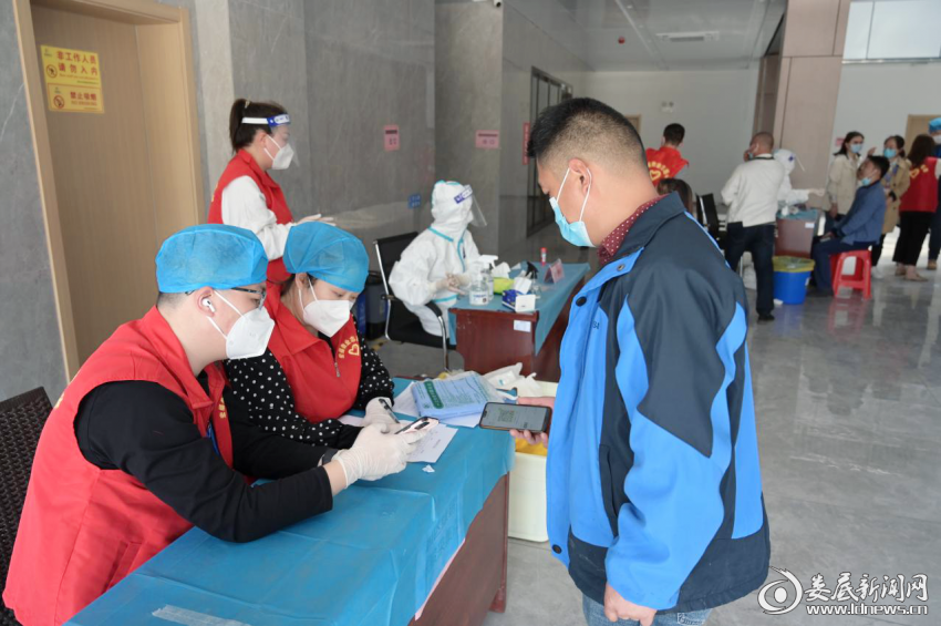 （在核酸检测点，志愿者正核对群众采样信息）