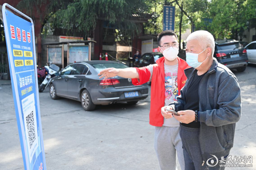 （志愿者在核酸监测点引导市民扫描场所码）