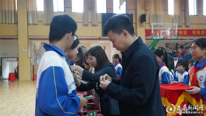 出席领导和嘉宾为新加入的共青团员佩戴团徽，并颁发团员证