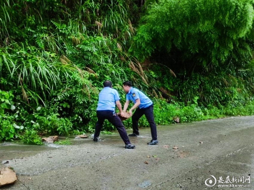 （新化县交通运输综合行政执法大队工作人员正在搬运路边乱石。）