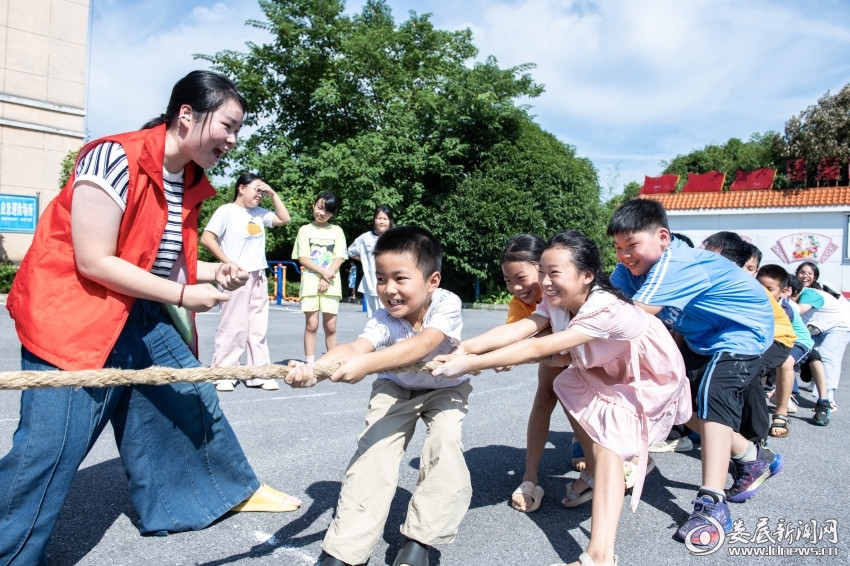7月26日，大学生志愿者和孩子们一起拔河。